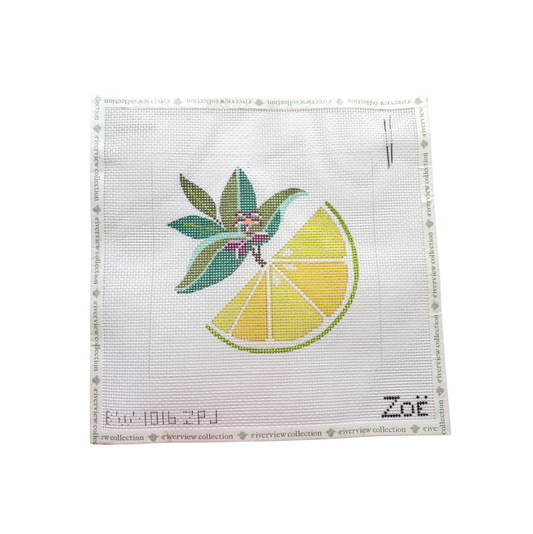 A square white needlepoint canvas featuring a stitched design of a yellow lemon slice and green leaves with small purple flowers.