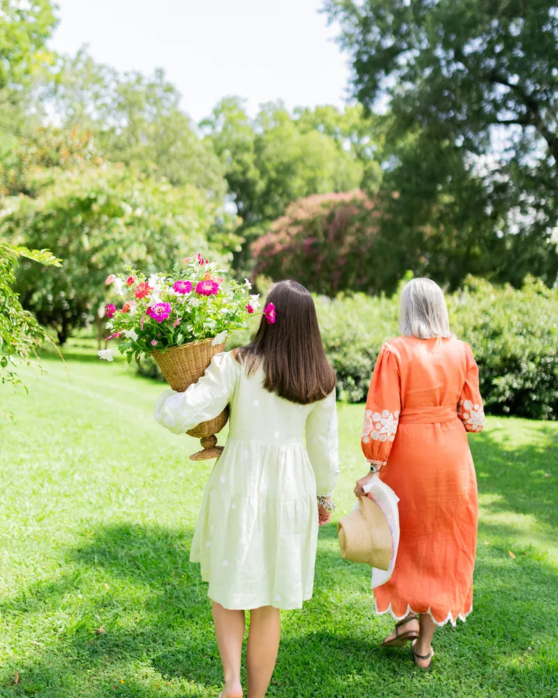 Margaret and Sibby walk through a garden carrying flowers at The Riverview Collection.